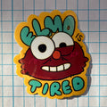 Sticker of a tired cartoon character with 'Elmo is Tired' text on a grid background
