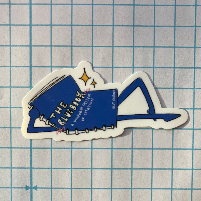Sticker of a blue notebook titled 'The Bluebook' on a grid background