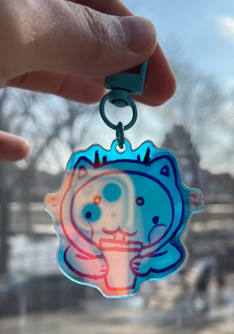 Hand holding a colorful keychain with a character design, blurred cityscape in the background