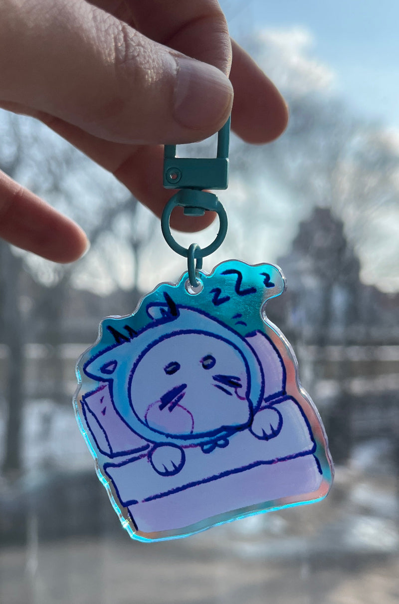 Hand holding a cartoon character keychain with a cityscape in the background