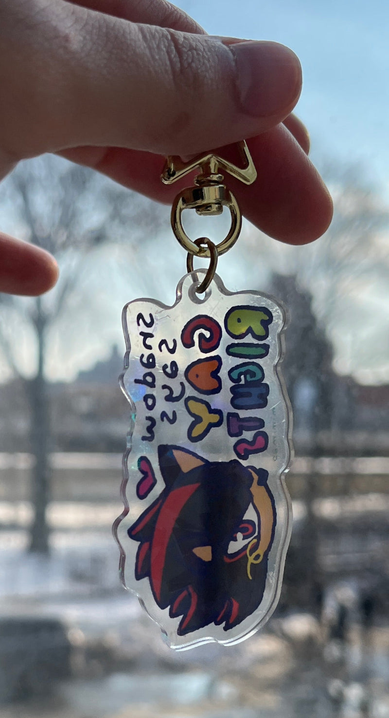 Keychain with colorful design held by a hand against a blurred outdoor background