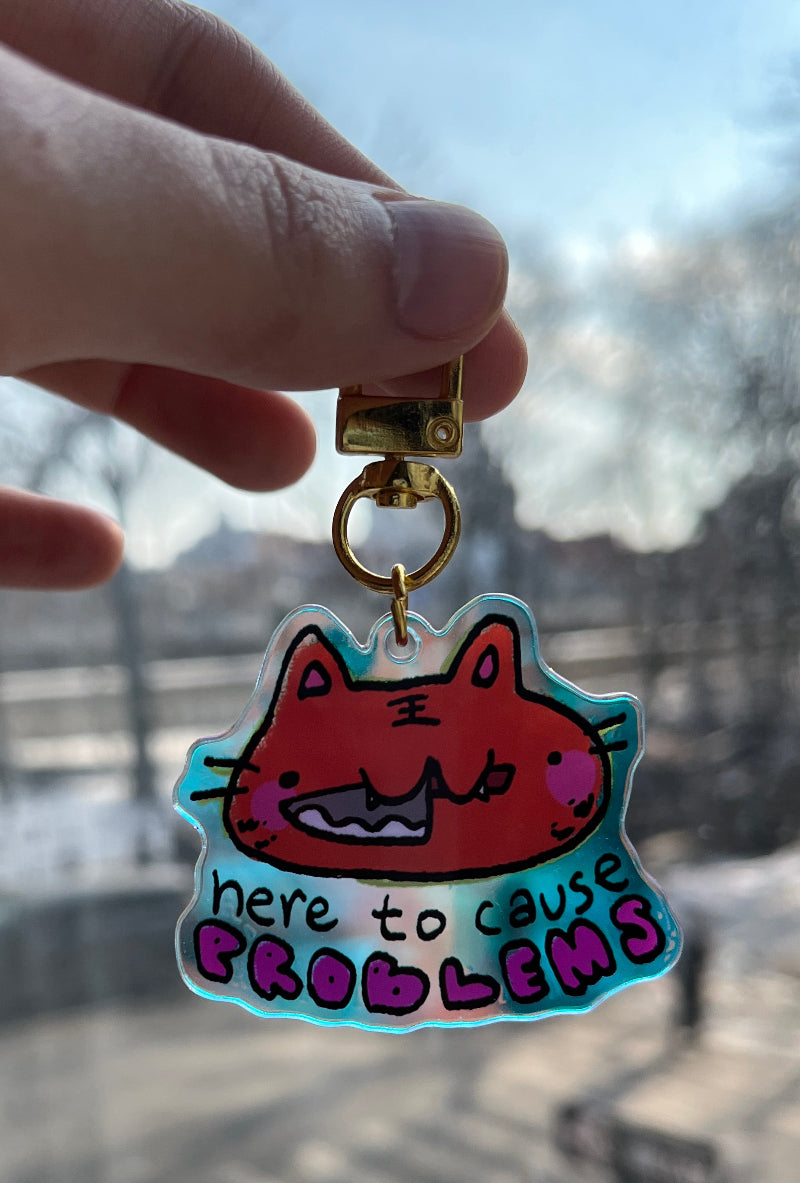 Keychain with cartoon character and text held in front of a cityscape