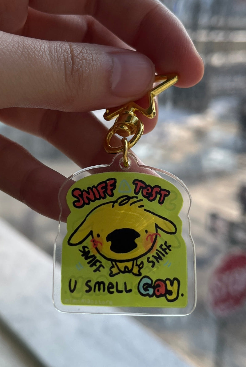 Hand holding a cartoon character keychain with a blurred outdoor background