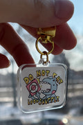 Keychain with cartoon character design held by a hand against a blurred outdoor background