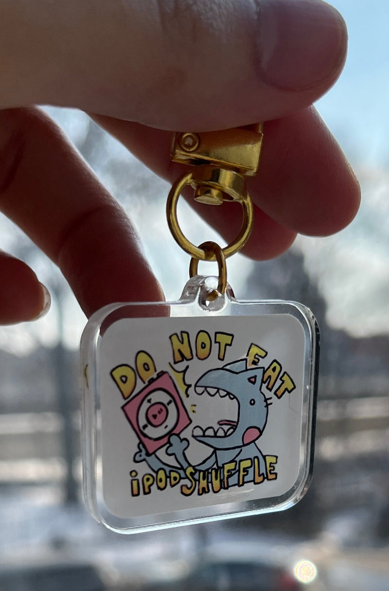 Keychain with cartoon character design held by a hand against a blurred outdoor background