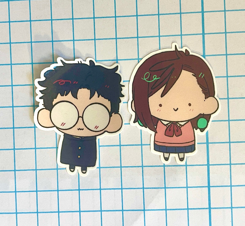 Two cartoon character stickers on a grid background